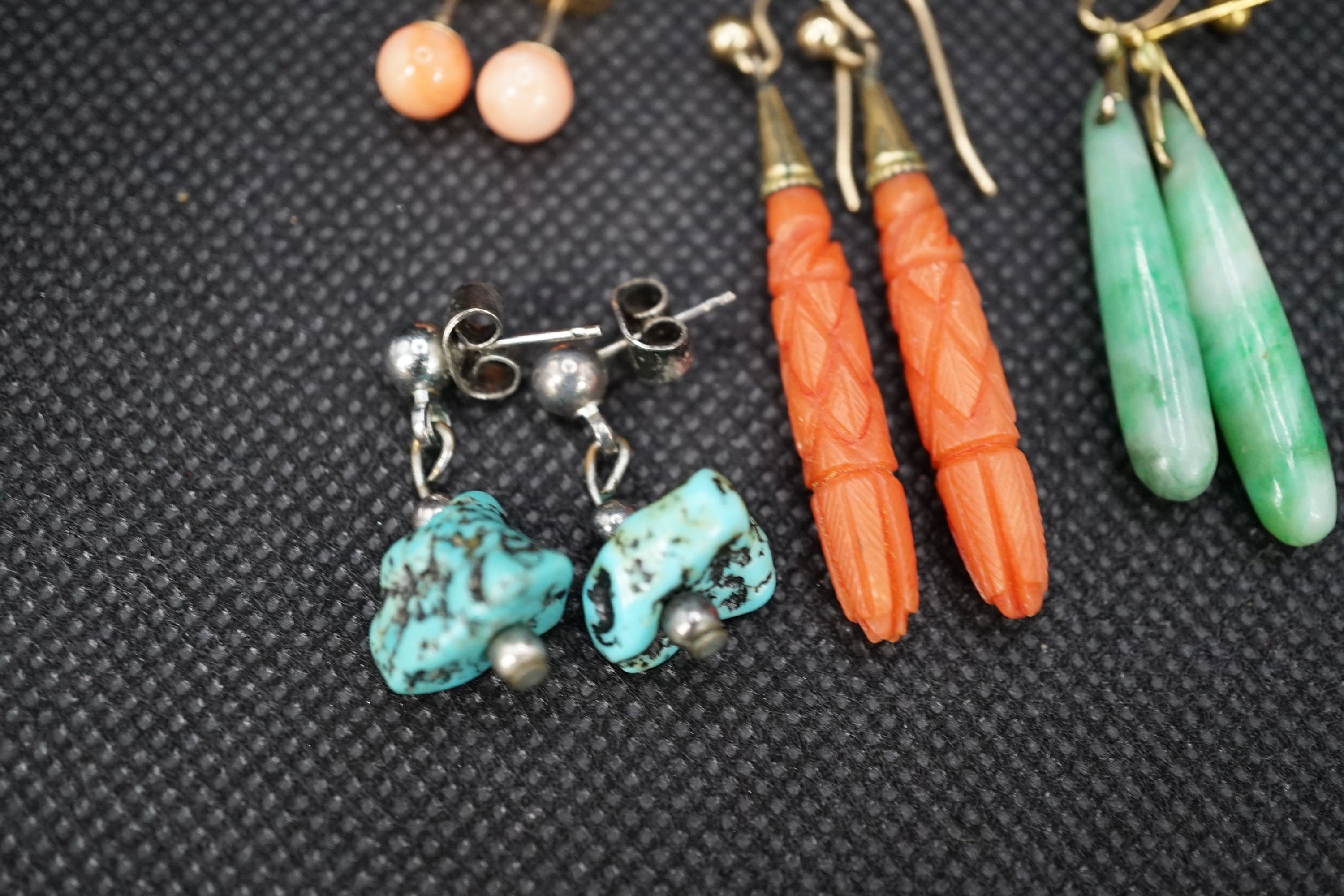 A pair of gilt metal and carved coral set teardrop shaped earrings, 38mm, a pair of similar shaped jade earrings and two other pairs of ear studs.